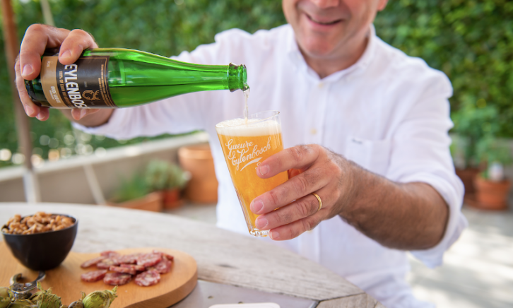 Man schenkt Eylenbosch Geuze in zittend aan een tafel met hapjes erop